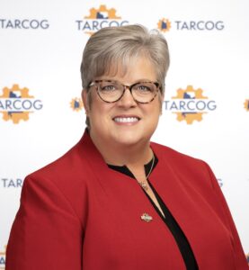TARCOG Board President Connie Spears in a red jacket in front of a white backdrop featuring TARCOG logos