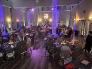 People sitting at tables in a beautifully decorated Studio 60 Senior Center for its Golden Gala.
